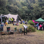 Families and volunteers taking part in outdoor nature activities at the Wardsend Cemetery Bioblitz, with information stalls and tents set up in a wooded clearing.