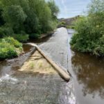 Baulk easement fish pass at Kelham Island Weir, showing a sloping beam creating a narrow water channel across the weir to help fish move upstream.