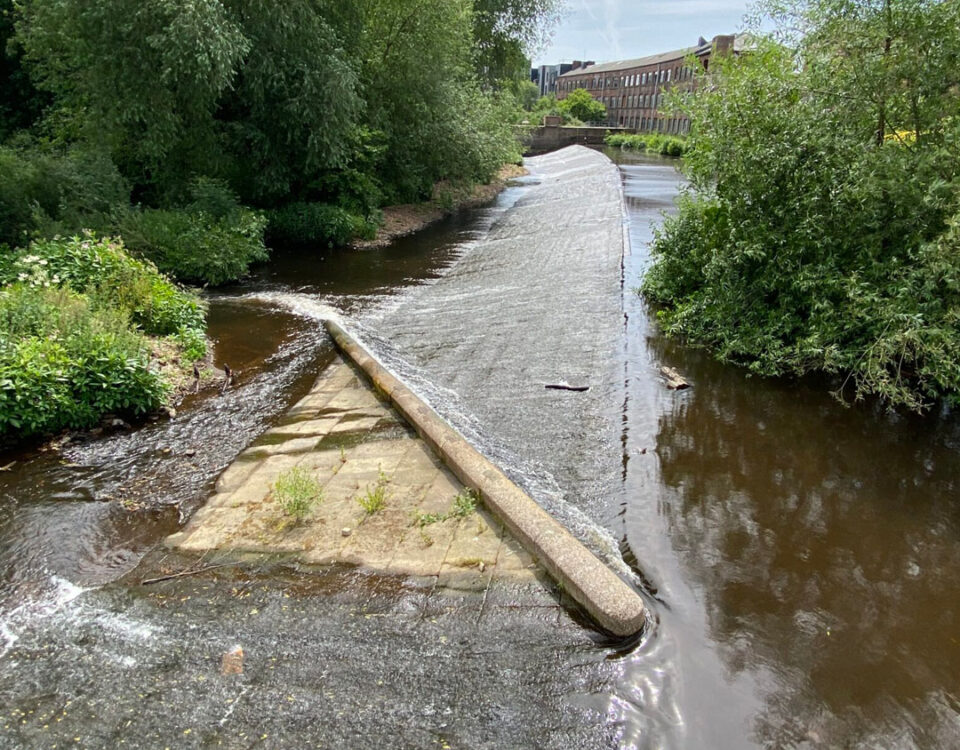 Baulk easement fish pass at Kelham Island Weir, showing a sloping beam creating a narrow water channel across the weir to help fish move upstream.